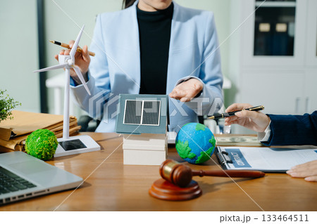 Two professionals plan global sustainability with eco housing, legal contracts, solar energy, and financial investment 133464511