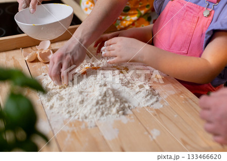 Family baking session, Children and adults kneading dough, Closeup of hands guiding dough preparation, Warm morning light highlights familial cooking bonding moments Family baking session, Children and adults kneading dough, Closeup of hands guiding dough preparation, Warm morning light highlights familial cooking bonding moments 133466620
