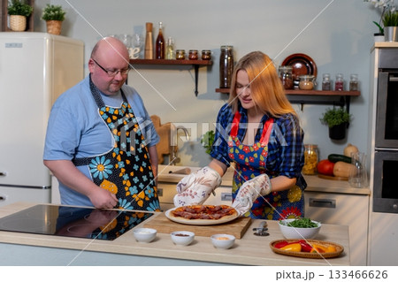 Couple preparing meal happily together, Joyful duo cooking in cheerful kitchen space, Partners sharing culinary experience amid cozy home surroundings and fresh produce Couple preparing meal happily together, Joyful duo cooking in cheerful kitchen space, Partners sharing culinary experience amid cozy home surroundings and fresh produce 133466626