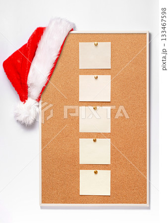 Blank note sheets are pinned to the board. Santa's hat on a cork board. Blank note sheets are pinned to the board. Santa's hat on a cork board. 133467598