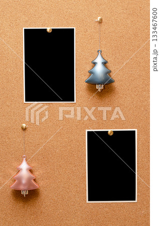 Empty photos and Christmas tree toys are pinned on a cork board. Copy space Empty photos and Christmas tree toys are pinned on a cork board. Copy space 133467600