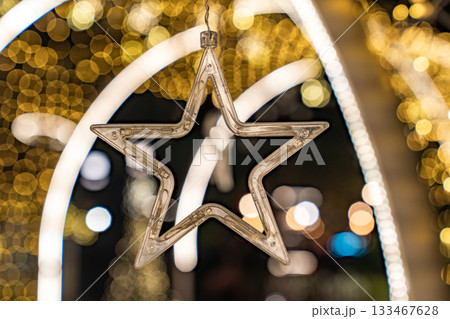 A star shaped clear light appears against warm golden bokeh, and the glowing circles form a gentle festive mood. 133467628