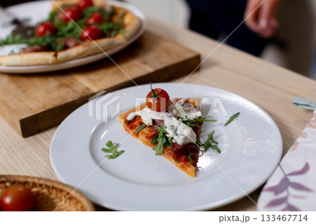 Indulge in a Delicious Slice of Gourmet Pizza Topped with Sweet Cherry Tomatoes and Fresh Arugula 133467714
