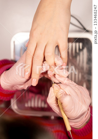 Artificial nails. Manicure therapy. Artist woman hands in pink protective latex gloves drawing acrylic varnish on tip with professional tool client care salon. Artificial nails. Manicure therapy. Artist woman hands in pink protective latex gloves drawing acrylic varnish on tip with professional tool client care salon. 133468247