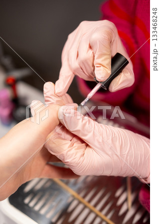 Manicure service. Care fingernails. Woman receiving professional hand treatment acrylic nail gel polish by beautician manicurist in protective latex gloves. Manicure service. Care fingernails. Woman receiving professional hand treatment acrylic nail gel polish by beautician manicurist in protective latex gloves. 133468248