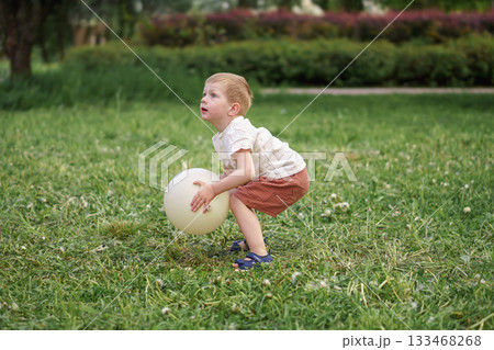 A Young Boy Enjoying Playing with a Colorful Ball in the Park Outdoors on a Bright Day 133468268