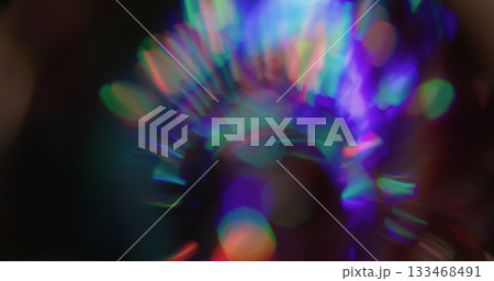 Round bokeh prism. Leak illumination. Neon color sphere shimmering kaleidoscope on black. Purple red green abstract blur background. 133468491
