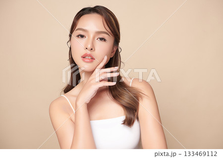 A beautiful young Asian woman with clean, fresh skin against a beige background. Skincare, facial treatment, cosmetology, beauty, and spa. An elegant portrait of an Asian woman. A beautiful young Asian woman with clean, fresh skin against a beige background. Skincare, facial treatment, cosmetology, beauty, and spa. An elegant portrait of an Asian woman. 133469112