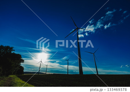 Majestic wind turbines stand against a vibrant sky at sunset, capturing the essence of renewable energy in a serene landscape 133469378
