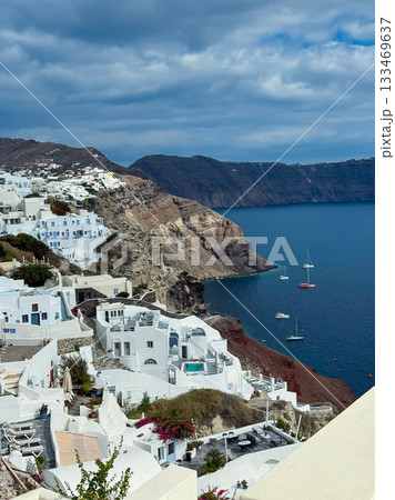 Discovering the stunning coastal beauty of Santorini as picturesque white buildings meet the azure waters under a cloudy sky 133469637