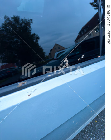 Visible damage on a parked car's window trim reveals wear and tear, capturing a moment of urban life in a quiet neighborhood during dusk 133469640