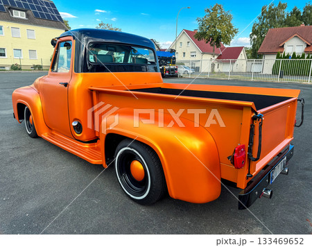 Classic orange truck shines under the bright sky in a vibrant neighborhood, showcasing vintage style and custom modifications in broad daylight Classic orange truck shines under the bright sky in a vibrant neighborhood, showcasing vintage style and custom modifications in broad daylight 133469652