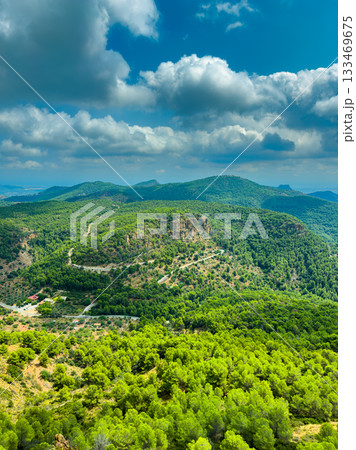 Exploring lush green mountains under a vibrant blue sky filled with fluffy clouds during a serene day in the countryside 133469675