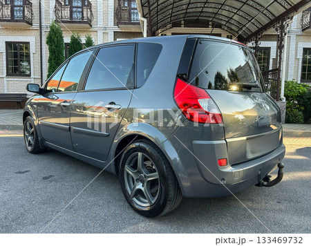 Shining grey car parked under a beautiful archway in a serene location, showcasing its sleek design and modern features during golden hour 133469732