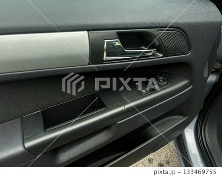 Details of a modern car door interior featuring sleek design, control buttons, and fabric texture captured in an urban setting on a cloudy day Details of a modern car door interior featuring sleek design, control buttons, and fabric texture captured in an urban setting on a cloudy day 133469755