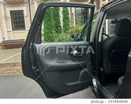 Car door swings open to reveal a quiet outdoor space with lush greenery and brick pathways, inviting exploration on a serene day 133469806