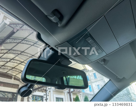 Mirror view captures interior details of a car parked under an elegant awning on a bright sunny day Mirror view captures interior details of a car parked under an elegant awning on a bright sunny day 133469831