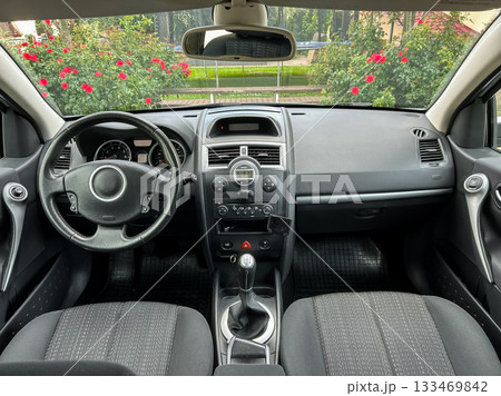 Interior view of a modern car showcasing clean design and comfortable seating while surrounded by lush greenery on a sunny day 133469842