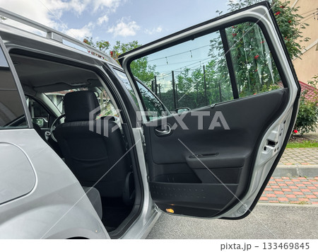 Open door reveals spacious interior of a modern vehicle on a sunny day in an urban neighborhood, inviting an adventure or casual outing with friends and family Open door reveals spacious interior of a modern vehicle on a sunny day in an urban neighborhood, inviting an adventure or casual outing with friends and family 133469845
