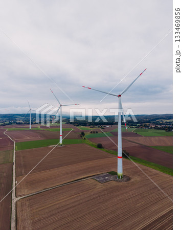 Wind turbines stand tall in a vast green landscape under an overcast sky during early morning hours, symbolizing sustainable energy and modern technology Wind turbines stand tall in a vast green landscape under an overcast sky during early morning hours, symbolizing sustainable energy and modern technology 133469856