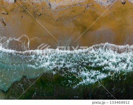 Breathtaking aerial view of golden beach and crashing waves under clear blue skies during a sunny day 133469912
