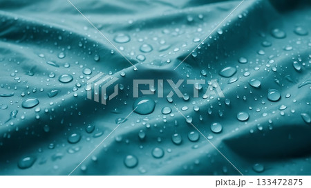 Closeup of water droplets on a turquoise fabric creating a textured pattern 133472875