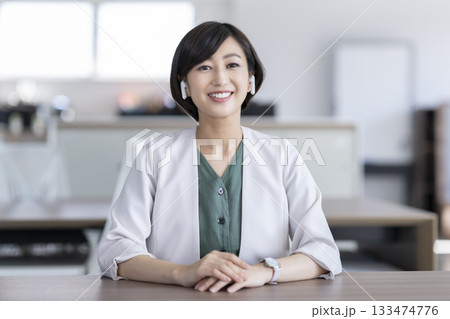 カメラ目線で話すイヤホンをつけた30代のビジネスウーマン カメラ目線で話すイヤホンをつけた30代のビジネスウーマン 133474776