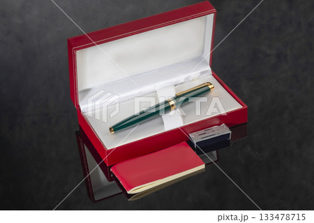 A branded fountain pen next to a box. Gift set. Selective focus. Office interior A branded fountain pen next to a box. Gift set. Selective focus. Office interior 133478715