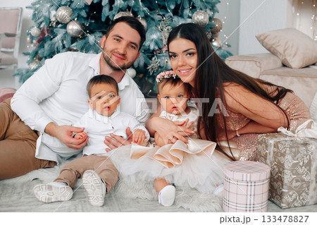 Family gathers together in front of a decorated Christmas tree with gifts and holiday cheer during a joyful celebration Family gathers together in front of a decorated Christmas tree with gifts and holiday cheer during a joyful celebration 133478827