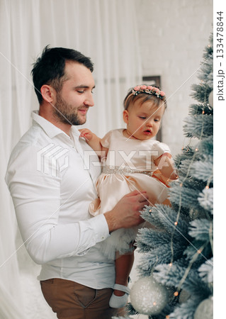 Father and daughter enjoy moments together decorating a Christmas tree in a cozy room filled with holiday spirit and joy Father and daughter enjoy moments together decorating a Christmas tree in a cozy room filled with holiday spirit and joy 133478844