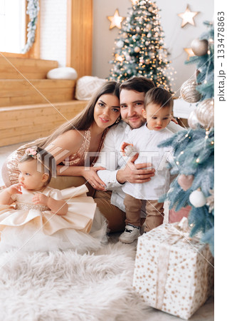 Family gathering at home during holiday season with a festive atmosphere and a beautifully decorated Christmas tree 133478863