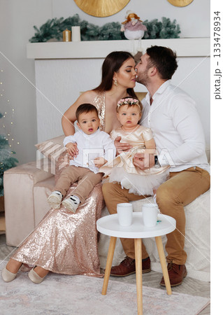 Family enjoying a special moment together in a cozy living room during a festive celebration Family enjoying a special moment together in a cozy living room during a festive celebration 133478934