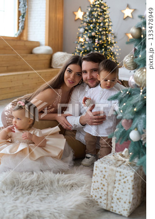 Family celebration with children during festive season in a cozy living room filled with decorations Family celebration with children during festive season in a cozy living room filled with decorations 133478949