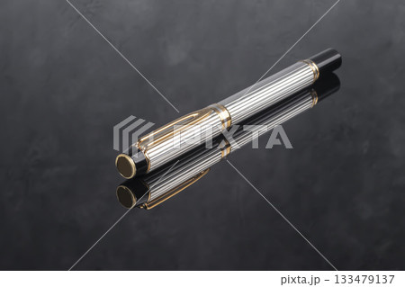 A branded fountain pen next to a box. Gift set. Selective focus. Office interior A branded fountain pen next to a box. Gift set. Selective focus. Office interior 133479137