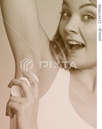 Girl applying stick deodorant in armpit. 133479998