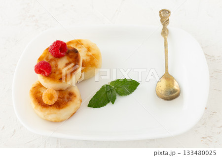 Curd fritters with raspberries on the white plate. 133480025