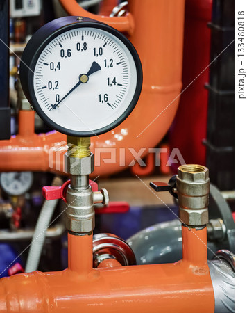 Pressure gauge shows reading on industrial pipes in a maintenance area with vibrant orange color Pressure gauge shows reading on industrial pipes in a maintenance area with vibrant orange color 133480818