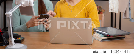 Two young asian woman using tablet and laptop computer for looking review of store in office. Two young asian woman using tablet and laptop computer for looking review of store in office. 133481413