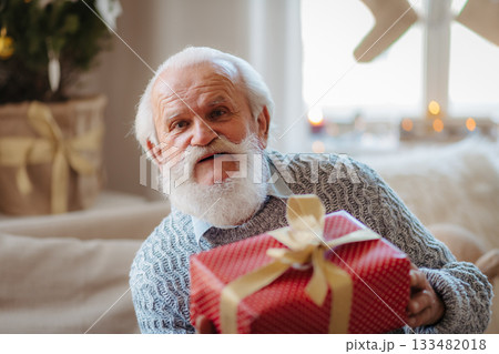 Senior man holding Christmas gift. Senior man holding Christmas gift. 133482018