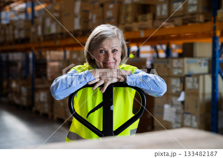 Senior woman manager or supervisor standing in a warehouse, arms crossed. Senior woman manager or supervisor standing in a warehouse, arms crossed. 133482187