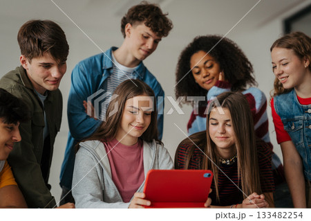Teen students learning together with digital tablet in modern classroom. 133482254