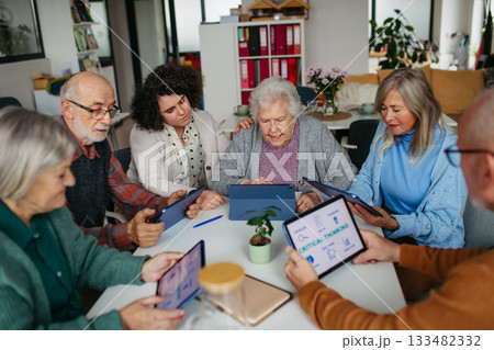 Group of senior people learning digital skills with tutor help. 133482332