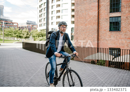 City commuter riding bike to office, wearing backpack and helmet. City commuter riding bike to office, wearing backpack and helmet. 133482371