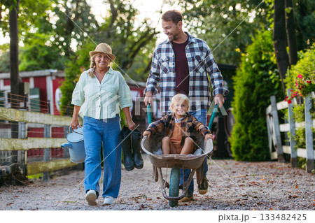 Father pushing toddler boy in wheelbarrow. 133482425