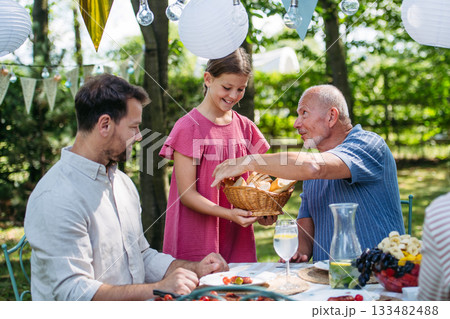 Family sharing food during garden grill party. Family sharing food during garden grill party. 133482488