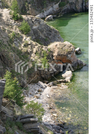 The photograph shows a rocky cliff on Olkhon Island, covered with coniferous trees. 133482491