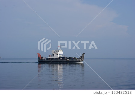 In the foreground is a platform-ferry for transporting cars and people to Olkhon Island. In the foreground is a platform-ferry for transporting cars and people to Olkhon Island. 133482518