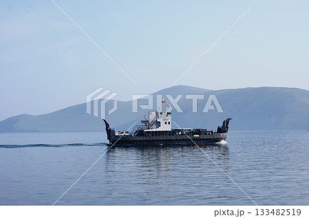 In the foreground is a platform-ferry for transporting cars and people to Olkhon Island. In the foreground is a platform-ferry for transporting cars and people to Olkhon Island. 133482519