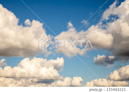 Fluffy white clouds float gracefully in a blue sky during mid-afternoon, creating a peaceful atmosphere Fluffy white clouds float gracefully in a blue sky during mid-afternoon, creating a peaceful atmosphere 133483221