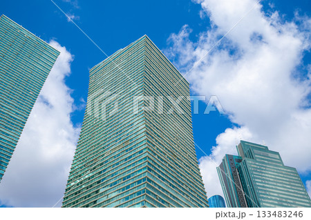 Modern turquoise glass towers skyscrapers on blue cloudy sky, view from below from street. glass facade and contemporary design. 133483246